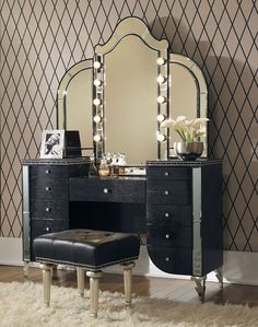 a black vanity with lights on it and a foot stool in front of the mirror