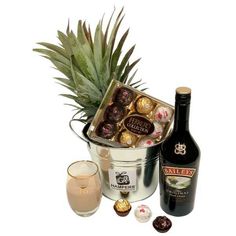 a pineapple and some chocolates in a bucket next to a bottle of wine