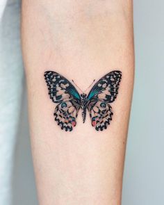 a small butterfly tattoo on the right arm and leg, it is blue with black spots