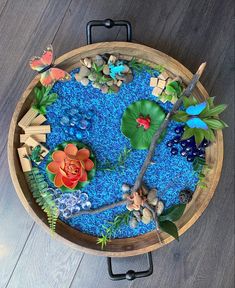 a wooden bowl filled with lots of blue and green plants on top of a wood floor