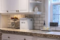 a kitchen with white cabinets and granite counter tops, an ice bucket on the sink