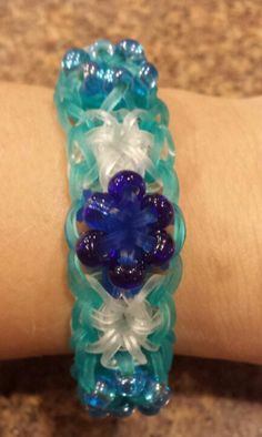 a woman's arm with a bracelet made out of glass beads and blue flowers