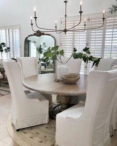 a dining room table with white chairs and a potted plant on top of it