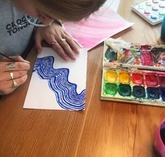 a woman is painting with watercolors on paper