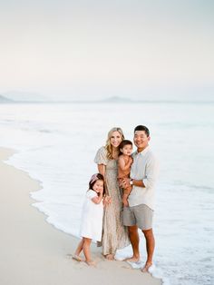 a family standing on the beach in front of the ocean