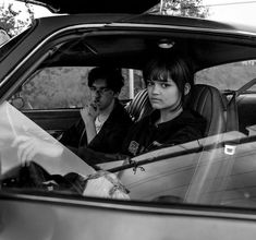 two people sitting in the back seat of a car