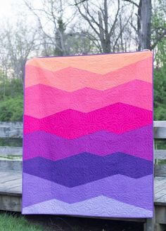 a colorful quilt sitting on top of a wooden bench