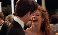 a man and woman laughing at each other in front of a group of people wearing tuxedos