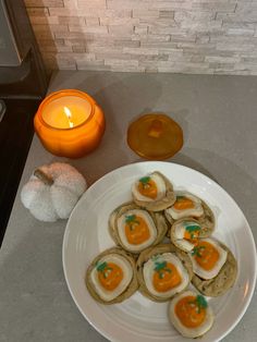 some food is on a white plate next to a candle and an orange lit candle