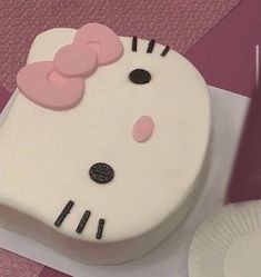 a hello kitty cake on a table with paper plates and utensils in the background