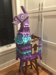 an animal made out of construction paper sitting on top of a wooden stool