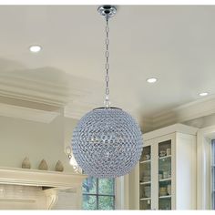 a crystal ball chandelier hanging from the ceiling in a kitchen with white cabinets