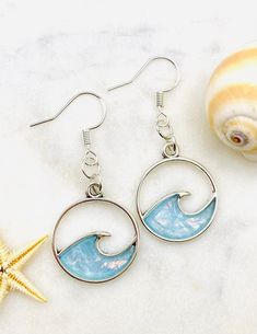 two seashells and one starfish on a white table with sea glass earrings