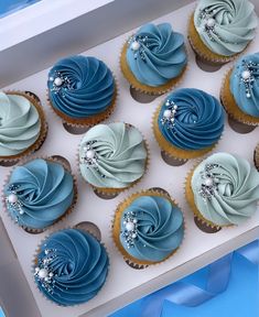 twelve cupcakes with blue frosting in a box