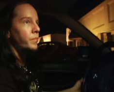 a man sitting in the passenger seat of a car at night with his hand on the steering wheel