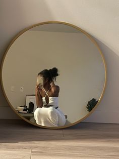 a woman sitting on the floor in front of a mirror