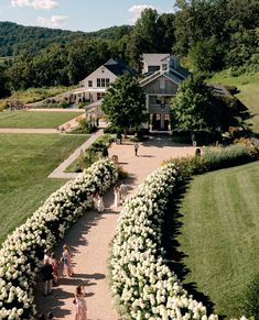 an aerial view of people walking down a path in front of a house