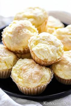 a black plate topped with muffins on top of a white table cloth next to a cupcake