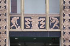 an entrance to a building with statues on the front and side walls, including two men working