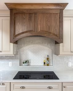 a stove top oven sitting inside of a kitchen next to wooden cupboards and white counter tops