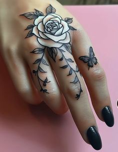 a woman's hand with a rose tattoo on it and butterflies around the ring