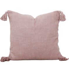 a pink pillow with tassels on the sides and a white back ground behind it