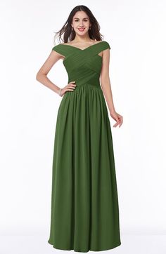 a woman in a long green dress with her hands on her hips, posing for the camera