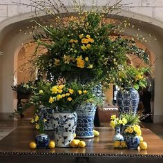 several blue and white vases with yellow flowers in them sitting on a wooden table