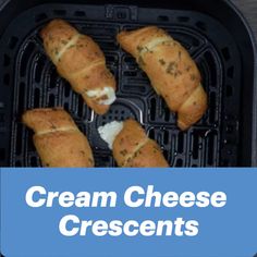 four pieces of bread sitting in an air fryer with the words cream cheese crescents