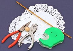 a pair of pliers and scissors on a doily next to a hole puncher