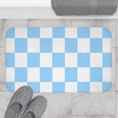 a blue and white checkered bathroom rug with slippers on the floor next to it