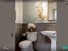 a white toilet sitting next to a sink in a bathroom under a mirror with gold accents