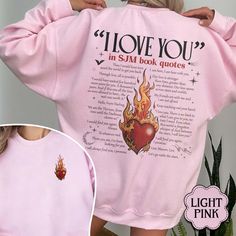 a woman wearing a pink sweatshirt with the words i love you in flames on it