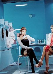 two women sitting on chairs in a room with washers and dryers behind them