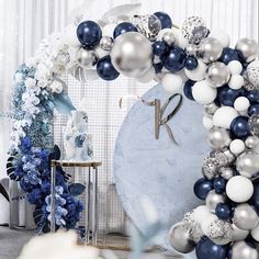 a blue and white balloon arch with the number one on it in front of flowers