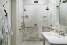 a bathroom with white towels hanging on the wall and two sinks in the shower area