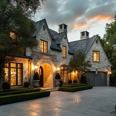 a large house with lots of windows and lights on it's front door, in the evening