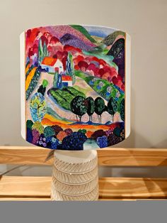 a lamp that is sitting on top of a wooden table in front of a painting