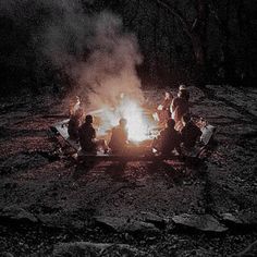 people sitting around a campfire in the dark