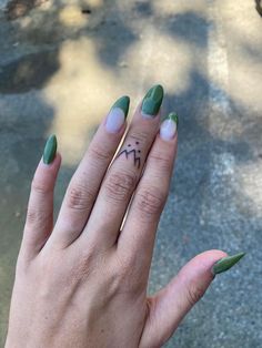 a woman's hand with green and white manicures holding up her ring