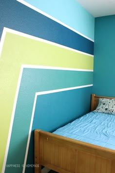 a bed sitting in a bedroom next to a blue wall with green and yellow stripes on it