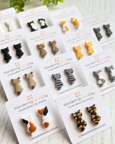 a bunch of small animal shaped pins on top of a white carded paper with orange and black cat designs