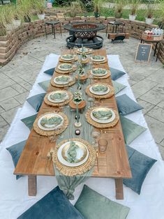 a long table set up with plates and place settings for an outdoor dinner party or gathering