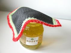 a bottle with a knitted cap on it sitting next to a jar filled with honey