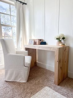 a white chair sitting next to a wooden desk in front of a window with curtains