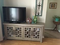 a flat screen tv sitting on top of a wooden entertainment center in a living room