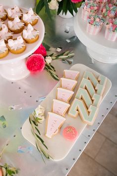 there are some cookies and other desserts on the table with pink flowers in the background