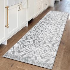 a large rug in the middle of a kitchen with white cabinets and wood flooring