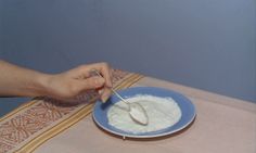 a person is spooning something out of a bowl on a table with a cloth