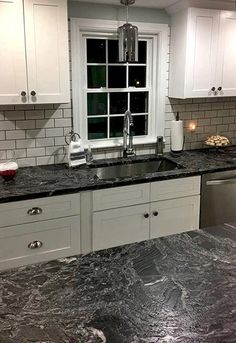 a kitchen with marble counter tops and white cabinets